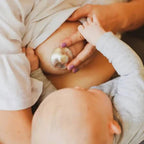 Close-up of a baby's hand touching a solyymoms silver nipple shield